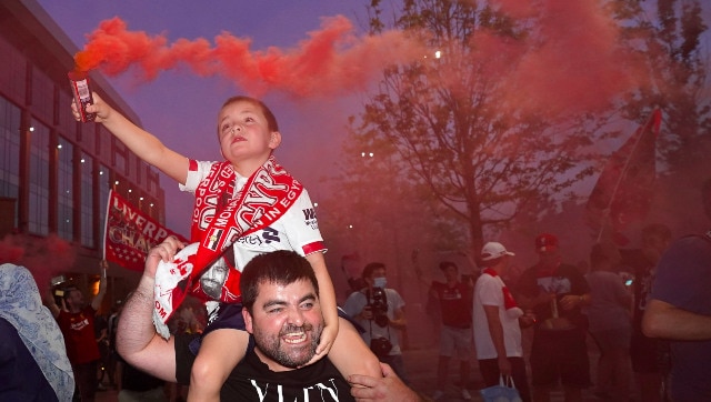 Un niño sostiene una bengala en la mano mientras los fanáticos celebran fuera del estadio del Liverpool, The Anfield.  AP
